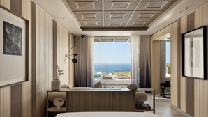 Une chambre d’hôtel moderne avec un grand lit, un bureau et une vue sur l’océan.