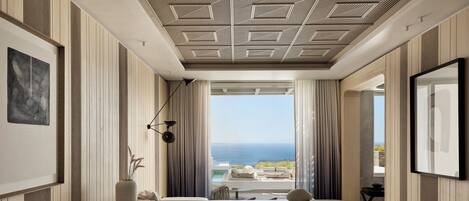Quarto de hotel moderno com uma cama grande, uma escrivaninha e vista para o oceano.