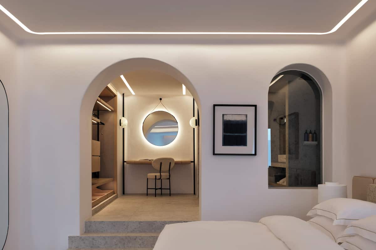Une chambre à coucher moderne avec un grand lit, un bureau avec une chaise et un miroir rond accroché au mur.