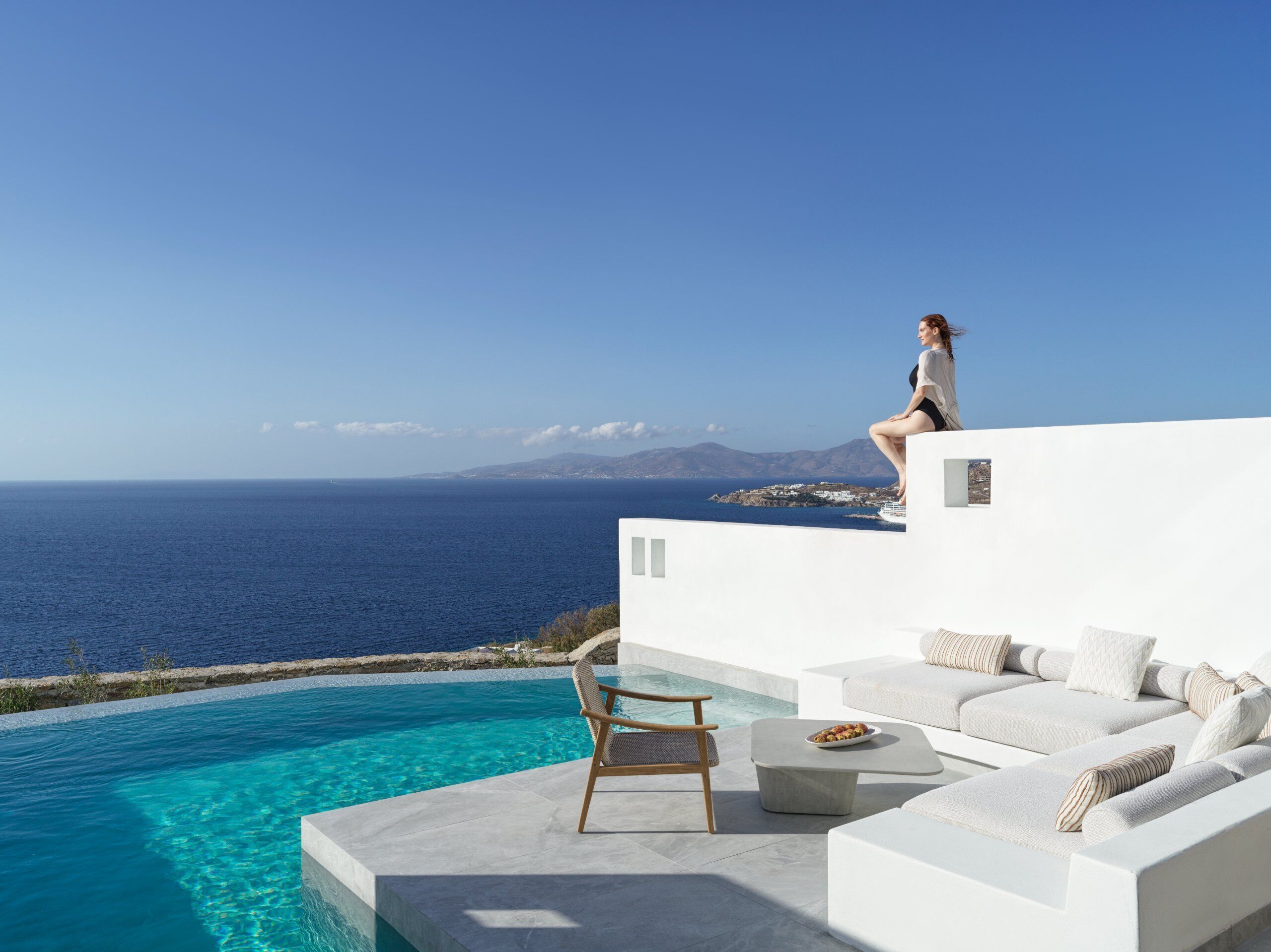 Un espacio moderno con asientos al aire libre, con piscina y vistas al mar.