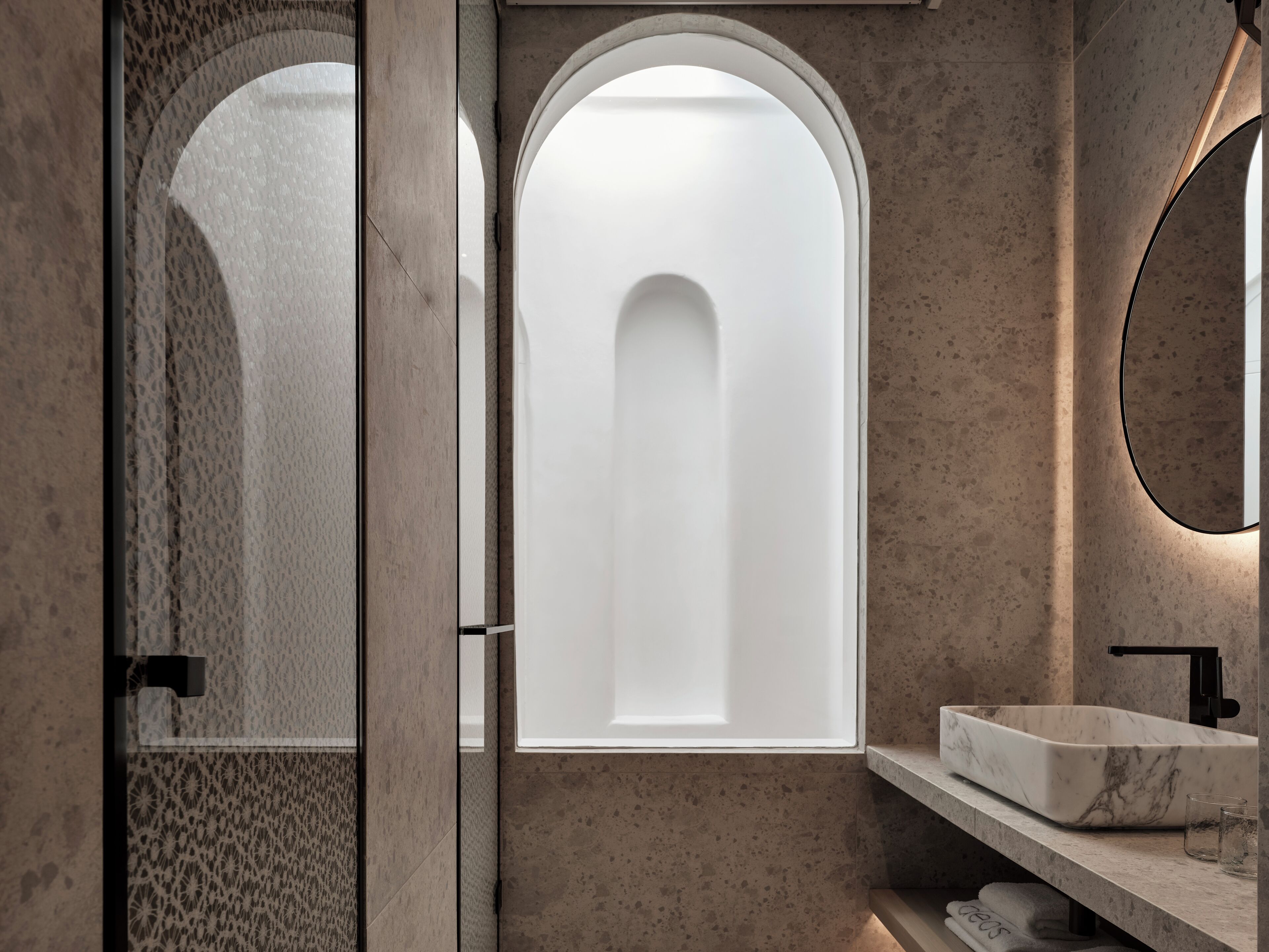 A modern bathroom with a marble sink, a large arched window, and a mirror.