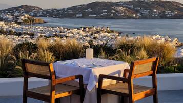 A table set for two with a view of a coastal town.