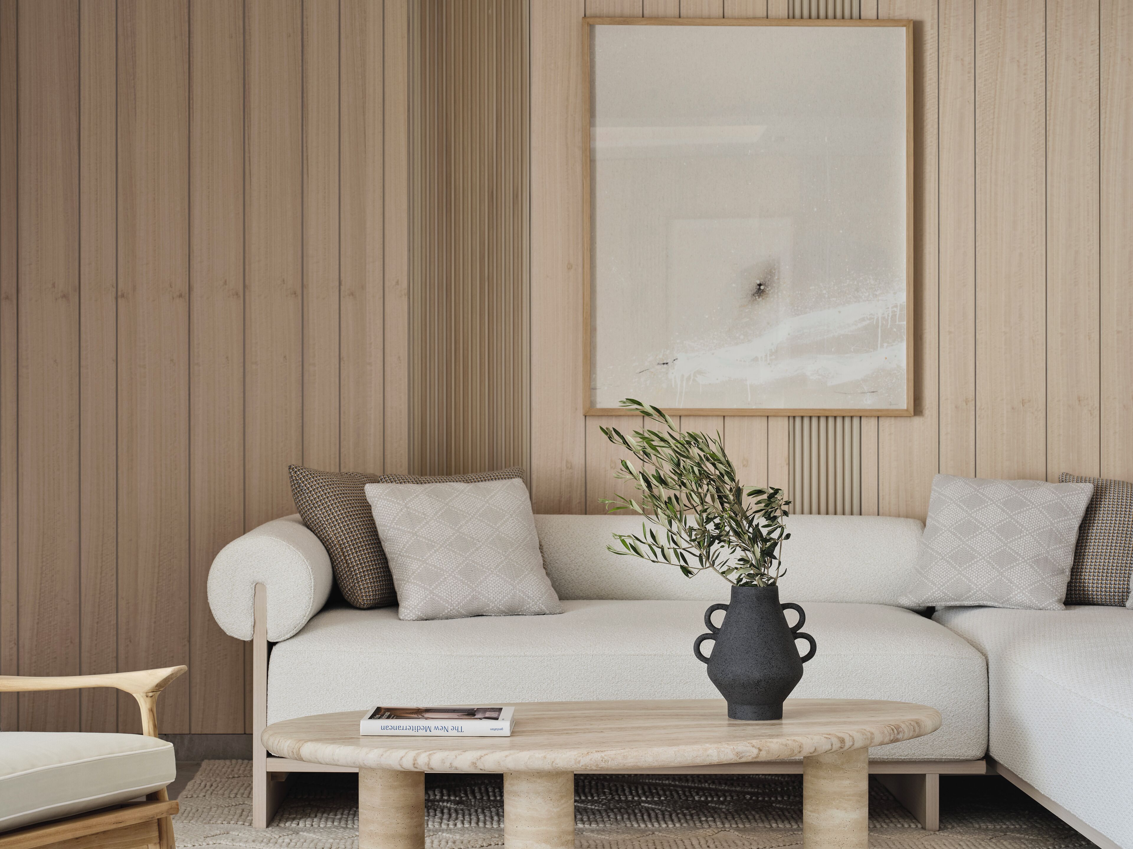 Un salon moderne avec un canapé, une table basse ronde et un vase avec des plantes.
