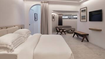 A modern hotel room with a large bed, a seating area with a table and chairs, and artwork on the walls.