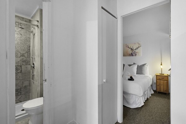 A bedroom with a bed, bedside table, lamp, and a painting on the wall.