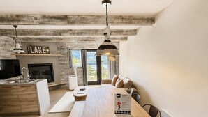 Cocina moderna con techo de madera, comedor con mesa de madera y vistas a un lago a través de amplios ventanales.