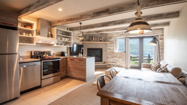 Una cocina moderna con electrodomésticos integrados, un comedor con una gran mesa de madera y una chimenea.