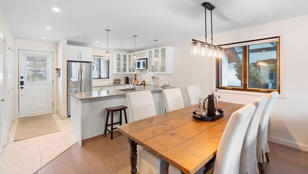 A modern kitchen with white cabinets, a central island, and pendant lighting. - Spacious Condo with Lake and Mountain View (Mont-Tremblant)