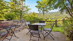 Un patio al aire libre con pared de piedra, una mesa y sillas.