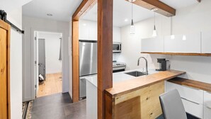 A modern kitchen with wooden beams, stainless steel appliances, and a wooden countertop.