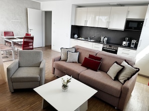 Ein modernes Wohnzimmer mit einer Couch, einem Couchtisch und einem Essbereich mit Stühlen.