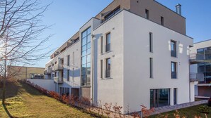 Un edificio residencial moderno de varios pisos con balcones, ventanas grandes y techo plano.