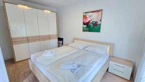 Un dormitorio con cama, mesita de noche, armario y un cuadro en la pared.