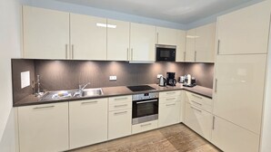 Una cocina moderna con armarios de colores claros, un microondas, una cafetera y un refrigerador.