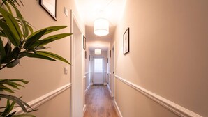 A hallway with wooden flooring, white walls, and framed pictures. - Luxury Living with Stunning Views (Southampton)