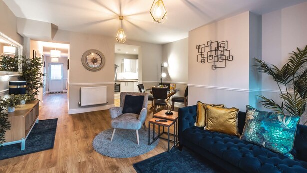 A modern living room with a blue sofa, a round coffee table, and a dining area in the background. - Luxury Living with Stunning Views (Southampton)