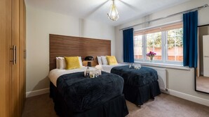 A bedroom with two beds, a wooden headboard, a ceiling light, a window with curtains, and a view of the outside. - Luxury Living with Stunning Views (Southampton)