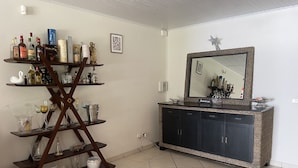 A bathroom with a wooden shelf holding various bottles and glasses, a sink with a mirror, and a star decoration on the wall. - Villa à la Campagne (Sainte -Luce)