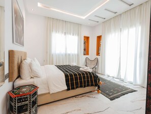 A modern bedroom with a large bed, a small side table, and a chair.