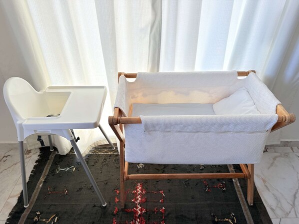 A room with a white chair, a small table, and a woven chair.