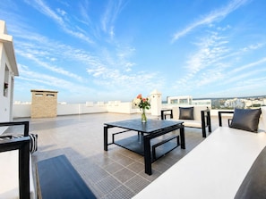 A rooftop terrace with a table, chairs, and a vase of flowers. - Rooftop Sea View Villa Near Beach (Essaouira)