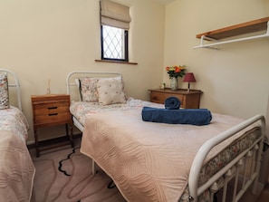 Une chambre avec deux lits, une fenêtre donnant sur un beau paysage, une table de chevet avec une lampe et une petite commode en bois.