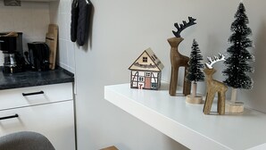 Eine Küche mit weißer Arbeitsplatte, einer Kaffeemaschine und einem kleinen Modell eines Hauses auf einem Regal.