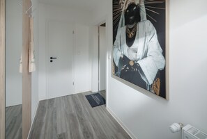 Enter a welcoming space with a coat rack for your belongings, a beautiful artwork, and a warm radiator.