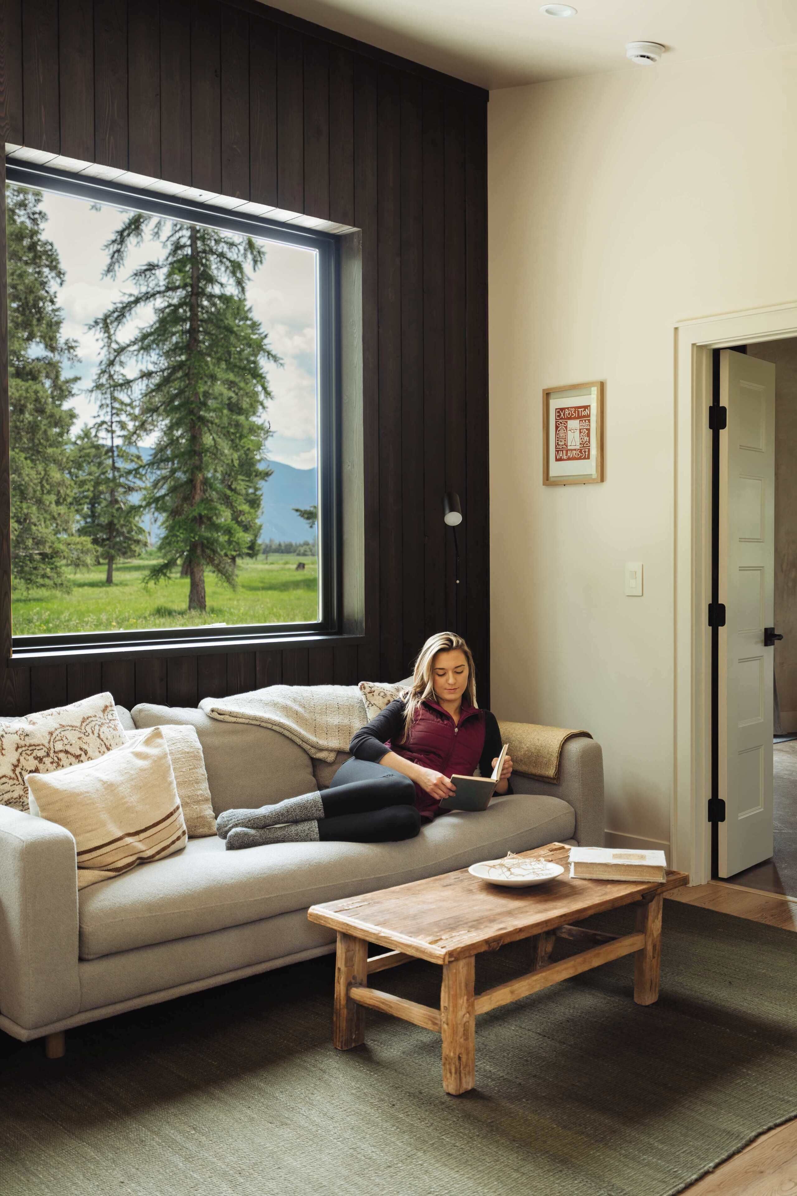 A room with a large window, a sofa, a coffee table, and a door.