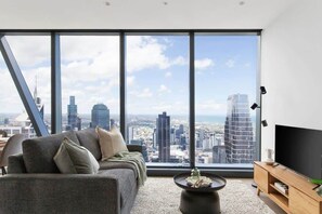 A modern living room with a large window, a sofa, a coffee table, and a TV.