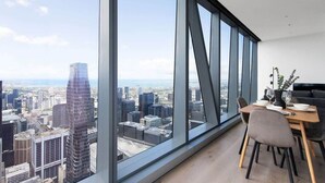 A modern dining area with a city view, large windows, and contemporary furniture. - A 2BR Apt with Amazing City Views, FREE Parking (Melbourne)