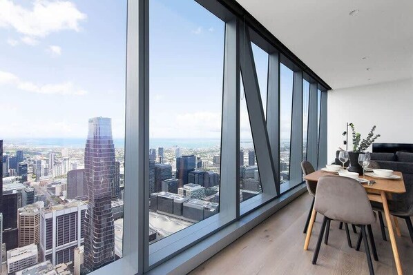 A modern dining area with a city view, large windows, and contemporary furniture.