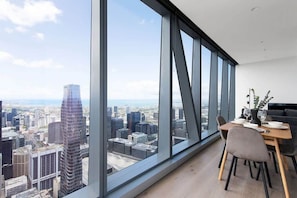 A modern dining area with a city view, large windows, and contemporary furniture.