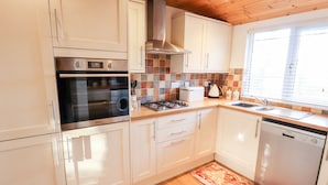 A modern kitchen with white cabinets, a stainless steel oven, a gas stove, and a dishwasher. - Kantankye Lodge (Skegness)