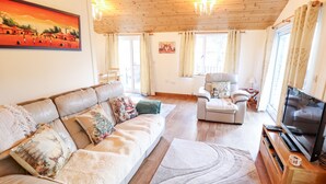 A cozy living room with a leather sofa, a recliner, a flat-screen TV, and a wooden coffee table. - Kantankye Lodge (Skegness)