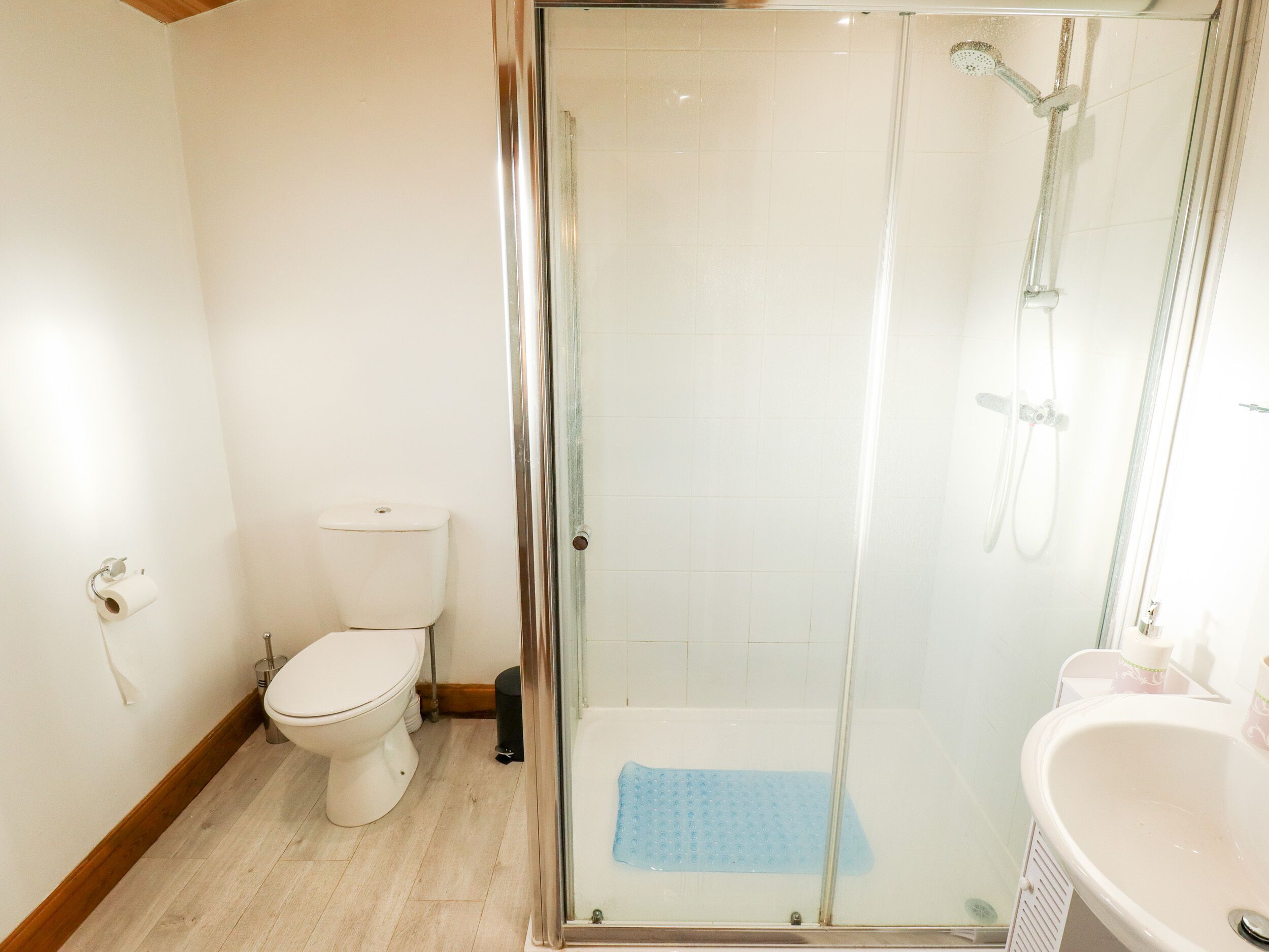 A bathroom with a glass-enclosed shower, a toilet, and a sink.