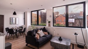 Eine moderne Wohnung mit Essbereich, einer Couch und großen Fenstern mit Blick auf Gebäude und Bäume.