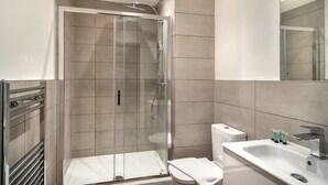 Ein modernes Badezimmer mit einer gläsernen Duschkabine, einem weißen Waschbecken und einer Toilette.