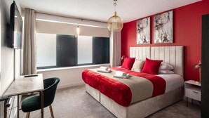 Ein modernes Hotelzimmer mit einem großen Bett, einem Schreibtisch und einem Fernseher.