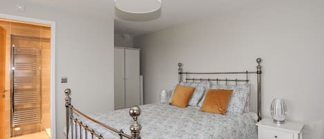 A bedroom with a metal-framed bed, a white bedside table, and a wardrobe.