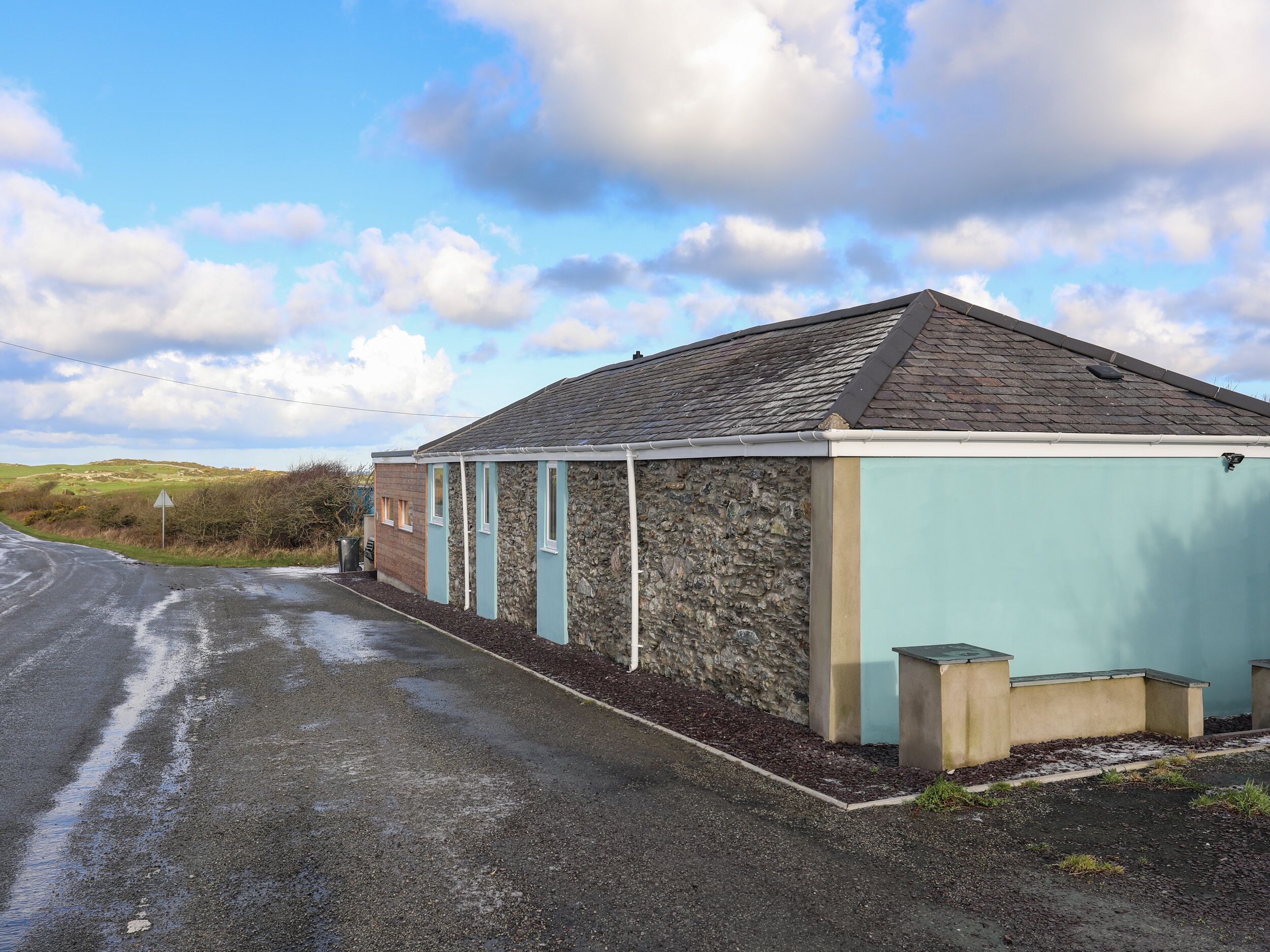 A single-story building with a stone facade and a light blue exterior.