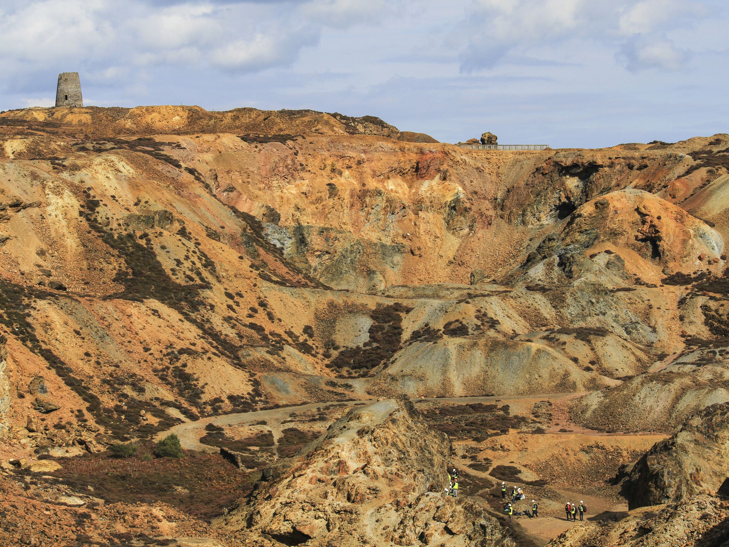 A rugged landscape with a prominent tower structure on a hill, surrounded by rocky terrain and sparse vegetation.