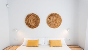 Ein Schlafzimmer mit einem Bett, zwei Nachttischen und zwei wandmontierten, runden Webdekorationen.