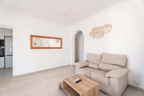 Ein Wohnzimmer mit einer Couch, einem Couchtisch, einem Wandspiegel und einer Wanddekoration.
