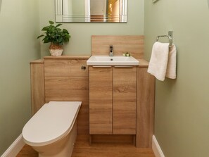 A bathroom with a wooden vanity, a white sink, and a toilet. - Summerseats Cottage (Alnwick)