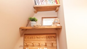 Ein Bücherregal aus Holz mit Büchern, einer kleinen Pflanze, einem Teddybären und einem Kleiderhaken mit Haken.