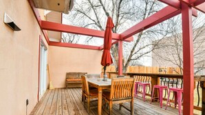 A wooden deck with a table and chairs, a red umbrella, and a wooden fence in the background. - Hazel @ Stella Ruby Cottages - Steps to Downtown (Moab)