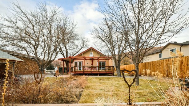 Une maison à deux étages avec un porche à l’avant, entourée d’une pelouse bien entretenue et d’arbres.