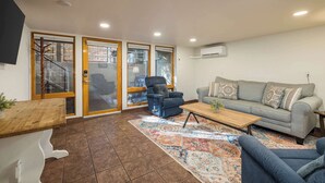 Un salon comprenant un canapé, des fauteuils, une table basse et un tapis à motifs.