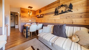 A cozy living room with a wooden wall, a dining area with chairs and a table, and a sofa with cushions. - Immodreams - La Fruitière - Avoriaz (Avoriaz)